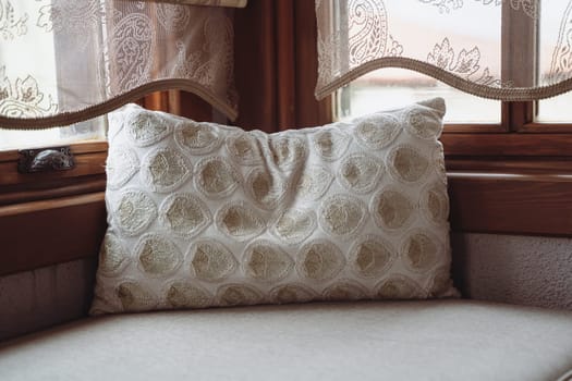 front view closeup of pillow with embroidery on divan in front of window