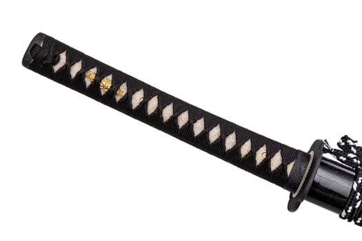 Close up shot of Tsuka - handle of Japanese sword wrapped by black silk cord on white ray skin with a small piece of gold decoration called Menuki isolated in white background. Selective focus.