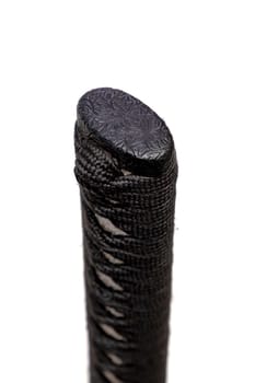 Close up the Kashira: butt cap (or pommel) made of steel on the end of the black silk cord wrapped handle Japanese sword isolated in white background. Selective focus.