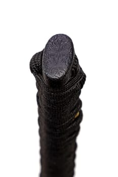 Close up the Kashira: butt cap (or pommel) made of steel on the end of the black silk cord wrapped handle Japanese sword isolated in white background. Selective focus.