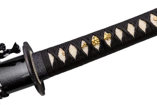 Close up shot of Tsuka - handle of Japanese sword wrapped by black silk cord on white ray skin with a small piece of gold decoration called Menuki isolated in white background. Selective focus.
