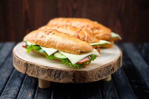 Hunter's sandwich with ham, cucumber, cheddar cheese on wooden board (photo with shallow depth of field)