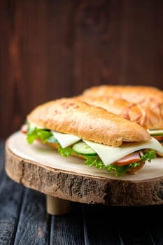 Hunter's sandwich with ham, cucumber, cheddar cheese on wooden board (photo with shallow depth of field)