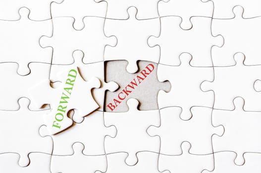 Missing jigsaw puzzle piece with word FORWARD, covering text BACKWARDS.  Business concept image for completing the final puzzle piece.