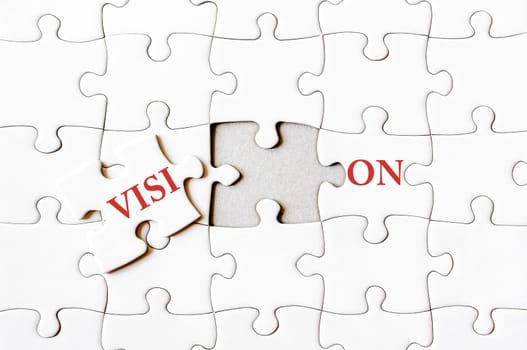 Missing jigsaw puzzle piece completing word VISION. Business concept image for completing the final puzzle piece.