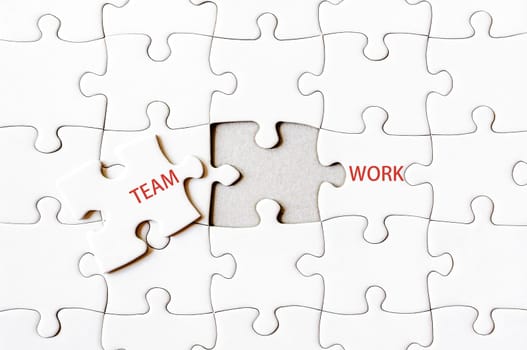 Missing jigsaw puzzle piece completing word TEAMWORK. Business concept image for completing the final puzzle piece.