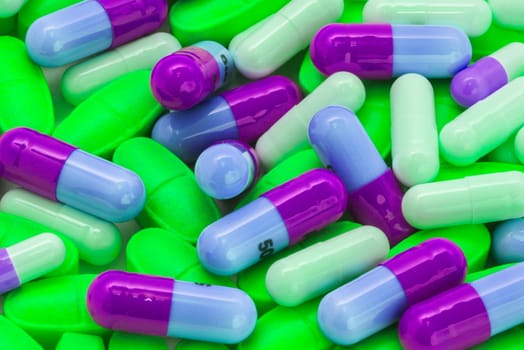 pile of green and blue-violet pills spilling on the table