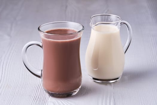 Cup of cappuccino and small creamer on wooden table