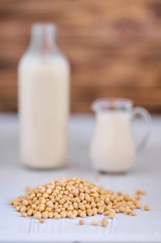 Bottle and pitcher of soy milk on white table (photo with shallow depth of field)
