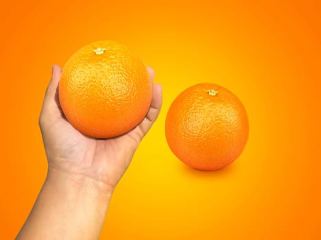 hand holding orange fruit and orange slices on orange background