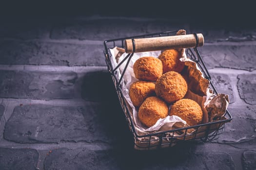 Homemade Arancini - deep fried rice balls stuffed with Mozzarella cheese in basket
