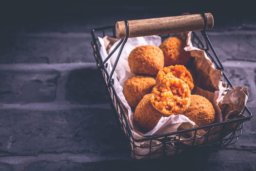 Homemade Arancini - deep fried rice balls stuffed with Mozzarella cheese in basket