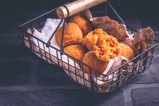 Homemade Arancini - deep fried rice balls stuffed with Mozzarella cheese in basket