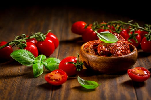 Sun dried and pickled tomatoes with fresh herbs, spices on wooden background