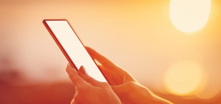 Woman hands holding smartphone at outdorrs in the evening. Close-up view.