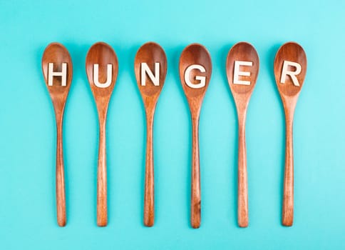Hungry is standing in german language on the wooden spoons, food shortage and starving because of the war and inflation, political issue
