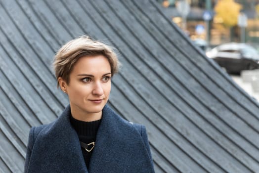 Portrait of an attractive short-haired blonde in the city in autumn.