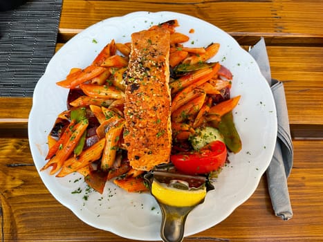 A plate of penne, pasta, vegetables and salmon.