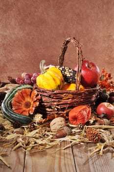 Pumpkins,apples,nuts,berries,corn and cereals with basket on old weathered wooden boards