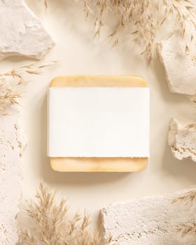 Soap bar with blank label near beige travertine stones and dried pampas grass top view, mockup. Boho scene handmade soap. Bohemian or close to nature .
