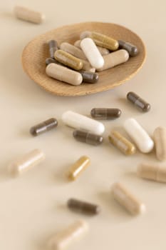 Mix of medical capsules in a bowl on light beige close up. Preventive medicine and healthcare, taking dietary supplements and vitamins. Assorted pharmaceutical medicine capsules