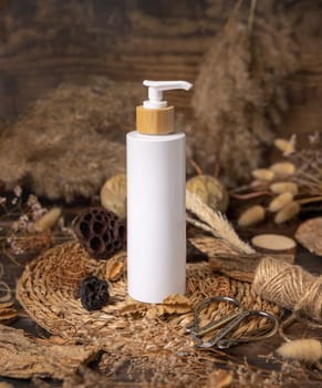 Cream one pump bottle on wood near natural boho decorations close up, cosmetics mockup. Eco friendly Skincare beauty product, lotion or balsam. Bohemian composition with dried leaves and flowers.