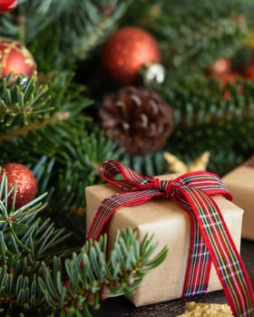 Wrapped gift boxes between Christmas decorations, pine cones and green fir branches close up. Christmas or New Year Holiday atmosphere flat lay