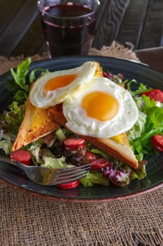 Fried eggs with toast, melted cheese and salad leaves