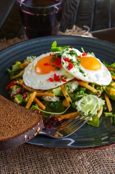 Fried eggs with avocado, salad leaves and crispy chips