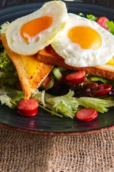 Fried eggs with toast, melted cheese and salad leaves