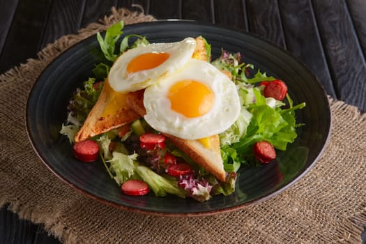 Fried eggs with toast, melted cheese and salad leaves