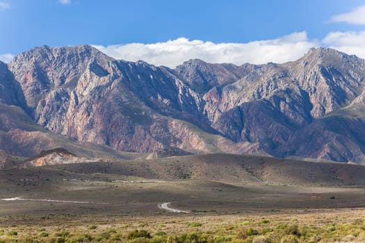 Rocky mountains with winding road on plateau  with green vegetation in karoo wilderness South Africa