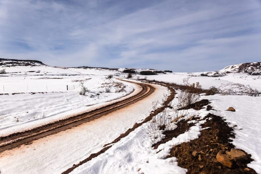 Dirt road tracks over  high plateau mountain terrain in winter snow scenic landscape