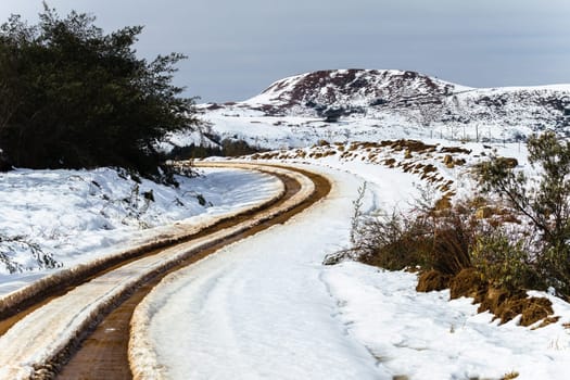 Dirt road tracks over  high plateau mountain terrain in winter snow scenic landscape