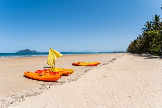 Kayak canoes on beach next to tropical blue ocean water at Mission beach south of Cairns Queensland Australia