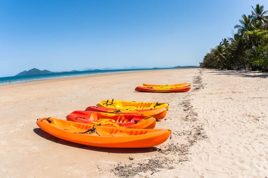 Kayak canoes on beach next to tropical blue ocean water at Mission beach south of Cairns Queensland Australia