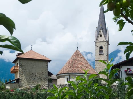 View of the church in St. Georgen near Schenna in South Tyrol framed by apple tree branches