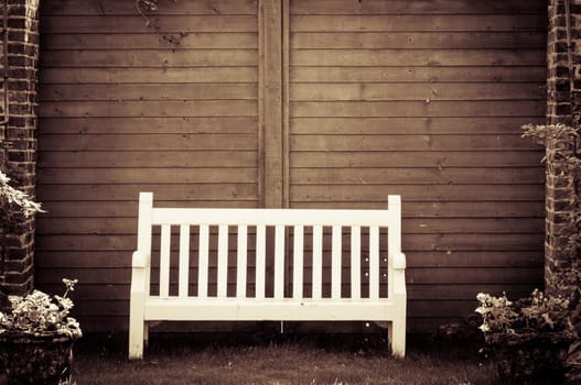 White Wooden garden bench in English garden, retro color filter applied