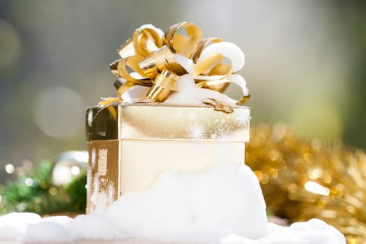 Golden Christmas background with present box on snow