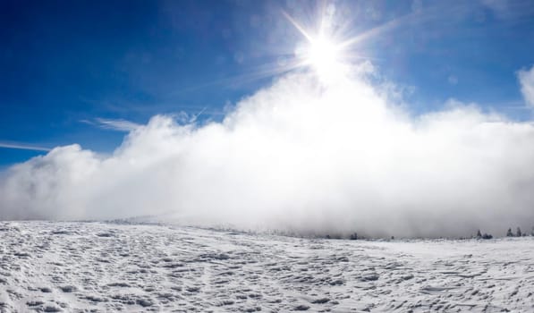 Winter landscape with snow covered hill and cloudy blue sky