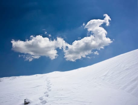 Winter landscape with snow covered hill and cloudy blue sky