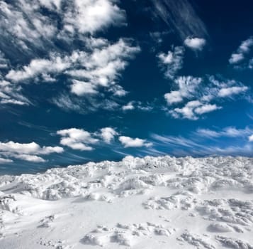 Winter landscape with snow covered hill and cloudy blue sky