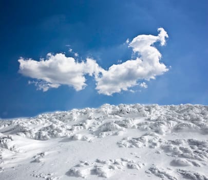Winter landscape with snow covered hill and cloudy blue sky