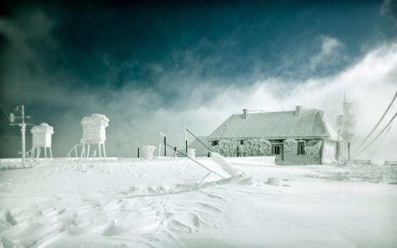Frozen cottage in the high mountains, covered with ice