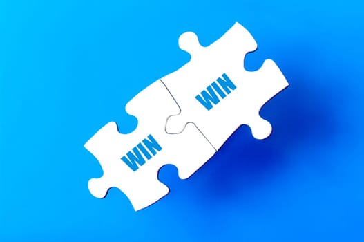 Connected puzzle pieces with words WIN and WIN  isolated over blue background, with copy space available. Business concept image.