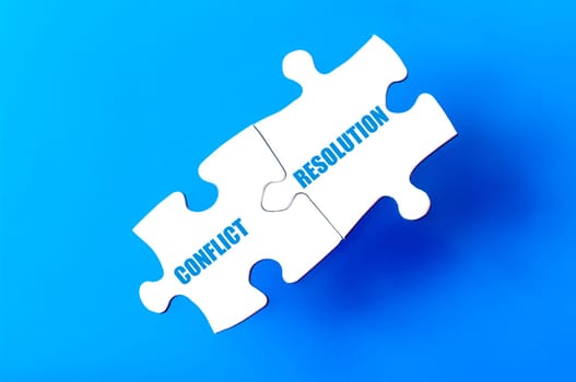 Connected puzzle pieces with words CONFLICT and RESOLUTION  isolated over blue background, with copy space available. Business concept image.
