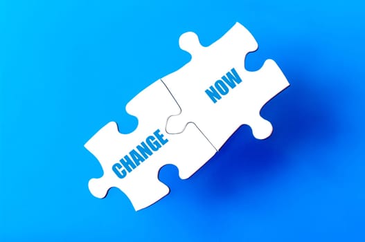 Connected puzzle pieces with words CHANGE and NOW  isolated over blue background, with copy space available. Business concept image.