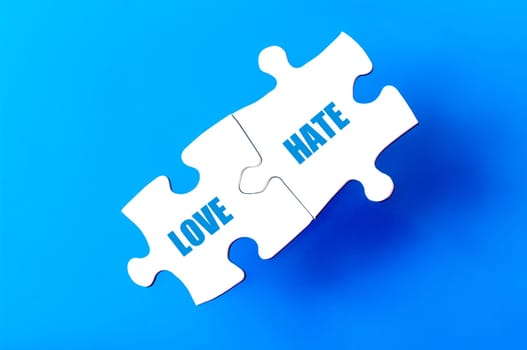 Connected puzzle pieces with words LOVE and HATE  isolated over blue background, with copy space available. Business concept image.
