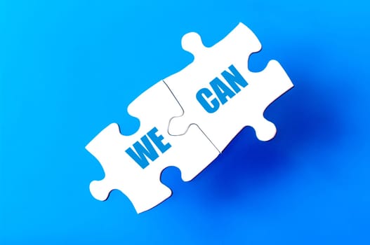 Connected puzzle pieces with text WE CAN  isolated over blue background, with copy space available. Business concept image.