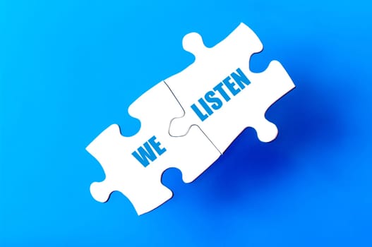 Connected puzzle pieces with text WE LISTEN  isolated over blue background, with copy space available. Business concept image.